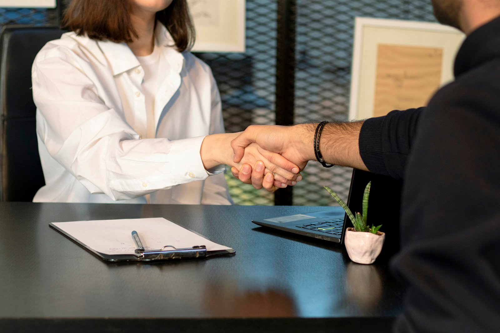 Employé d'une agence d'intérim serrant la main d'un travailleur dans un bureau