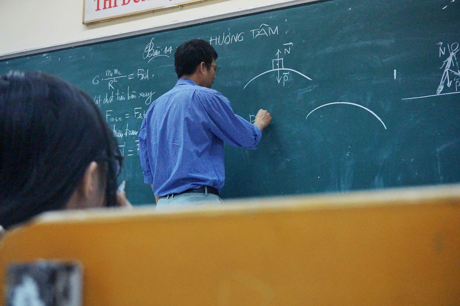 Main d'un enseignant écrivant un calcul de salaire au tableau