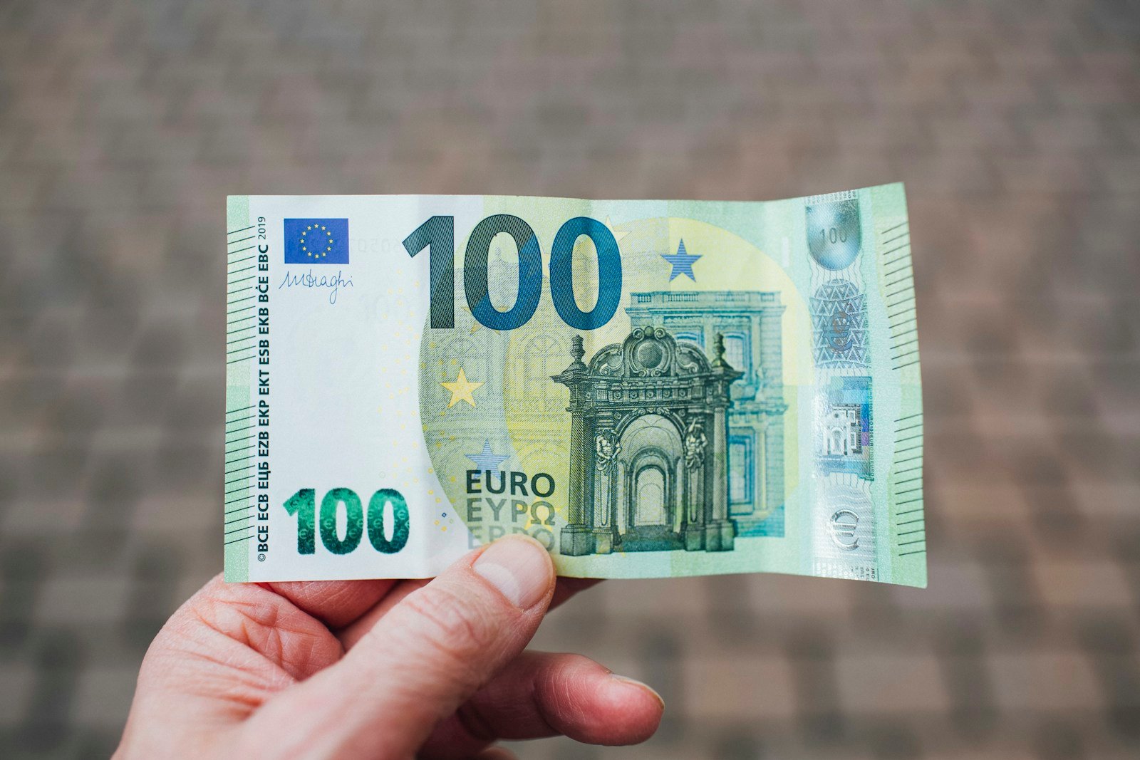 Main tenant des billets d'euros illustrant le doute sur l'existence du billet de 1000 euros