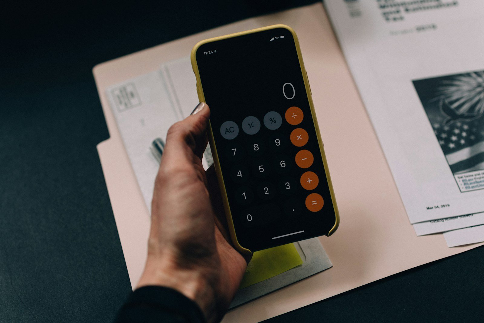 Mains tenant un bulletin de salaire et une calculatrice à côté d'un calendrier