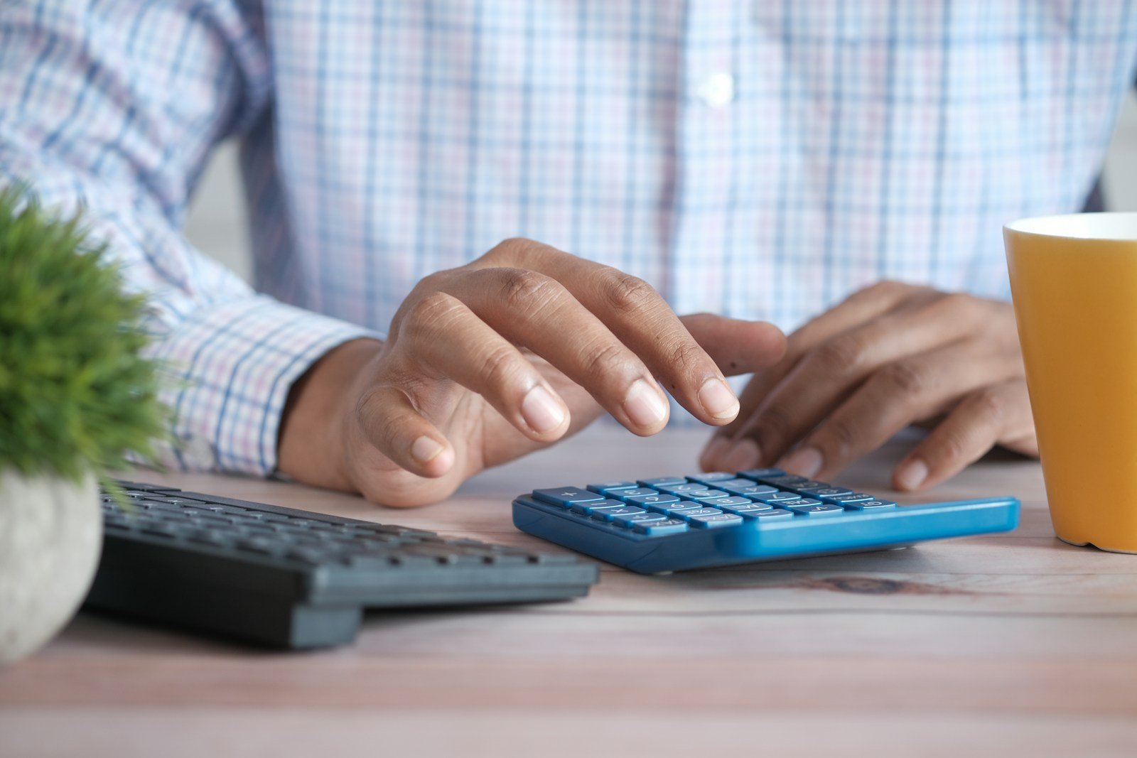 Parent calculant les indemnités de sa nounou avec une calculatrice et des documents