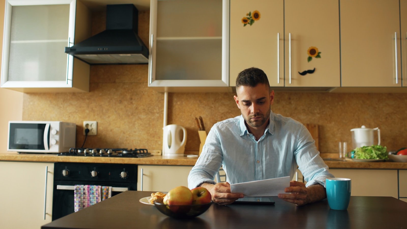 Personne assise à une table de cuisine consultant des courriers officiels et un ordinateur portable
