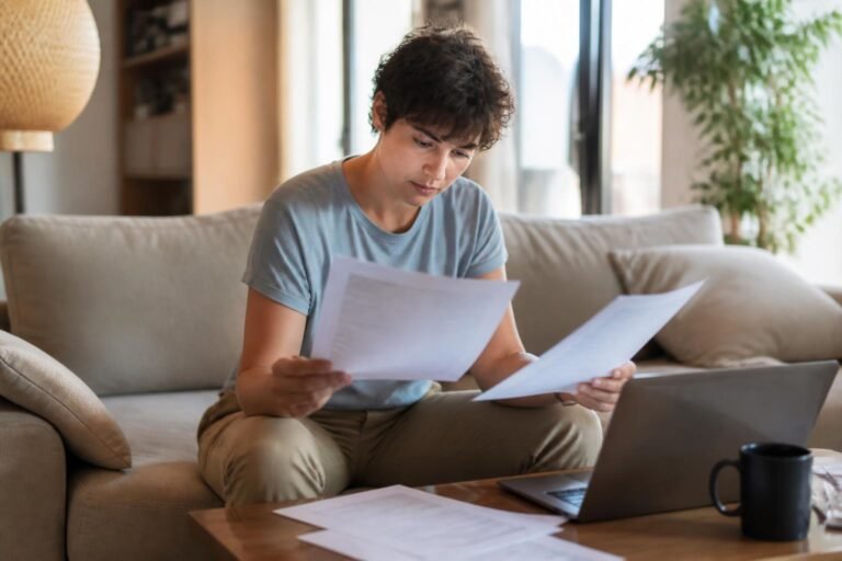 Personne au repos chez elle lisant des documents médicaux et administratifs sur un canapé