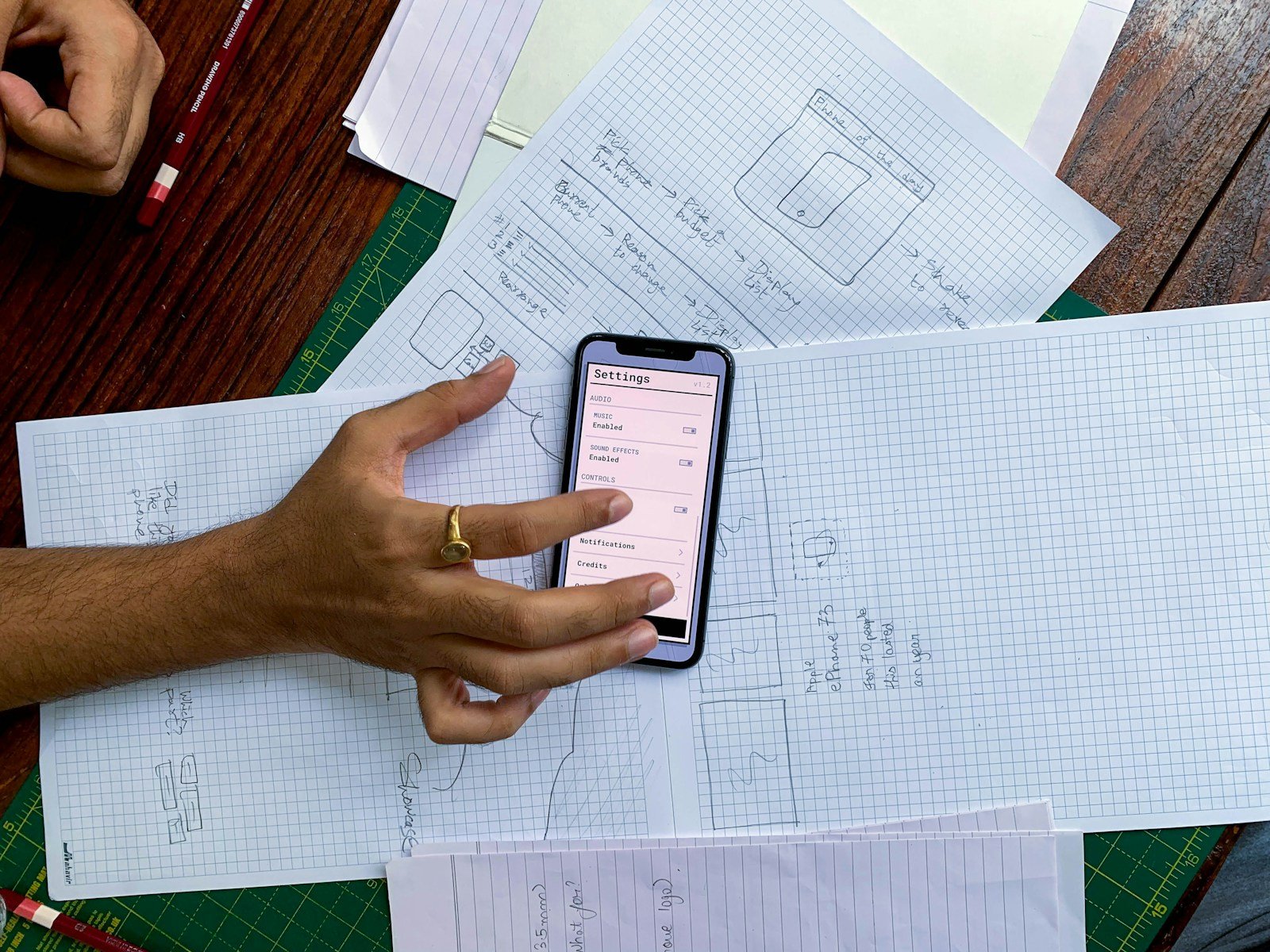 Personne au téléphone prenant des notes avec des documents étalés sur une table