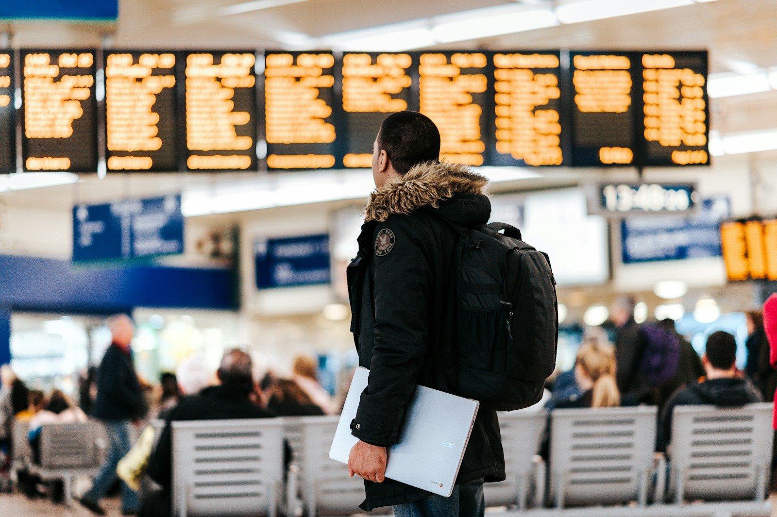 Tableau des départs et voyageurs avec bagages dans le hall de l'aéroport