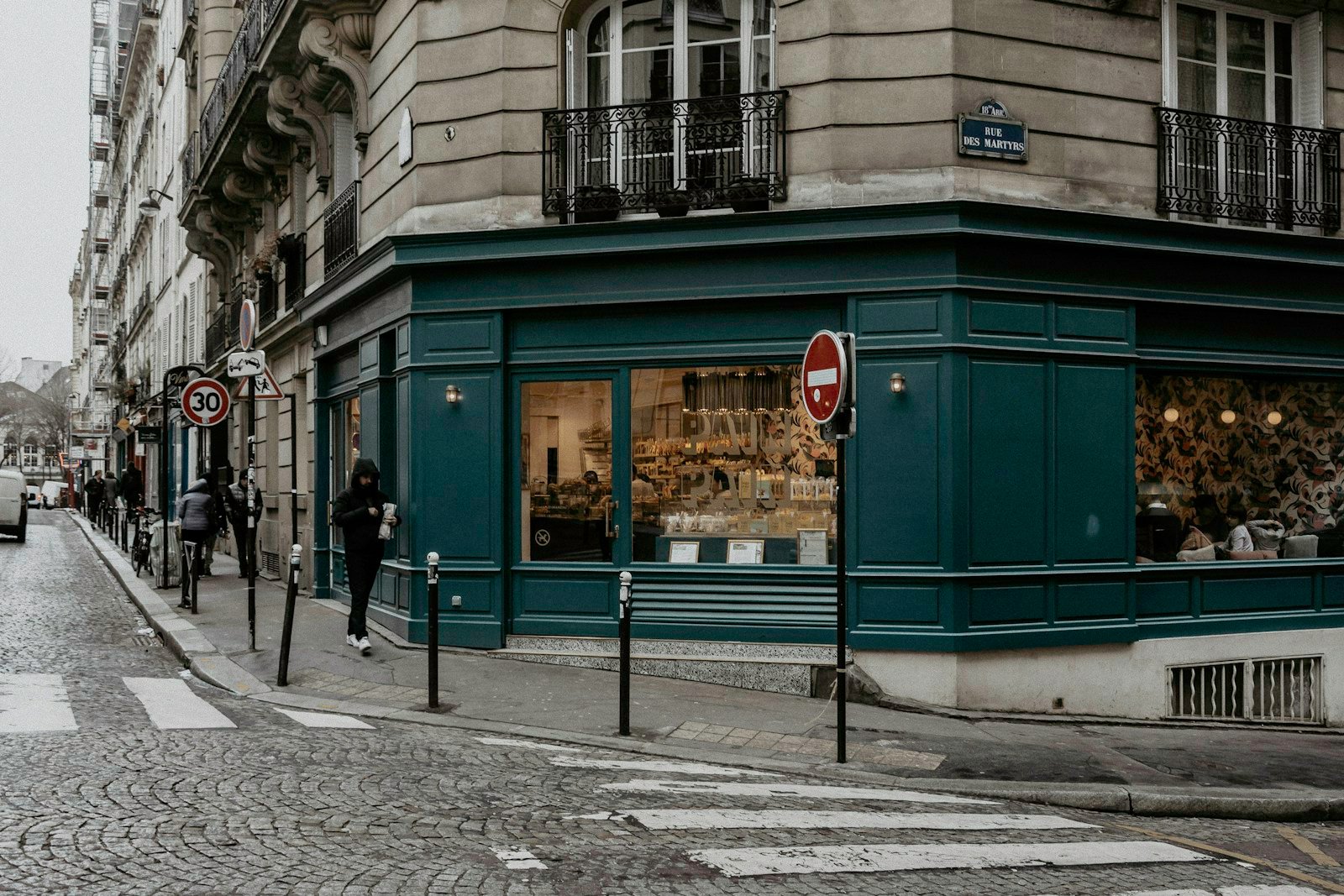 Une pharmacie fermée et sa croix verte au crépuscule dans une rue d'Alès