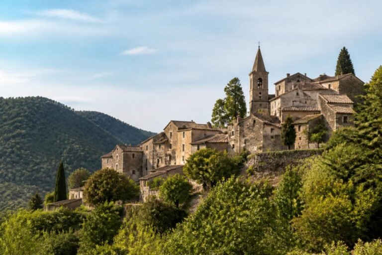 Village médiéval des Cévennes perché sur sa colline, maisons de pierre et clocher